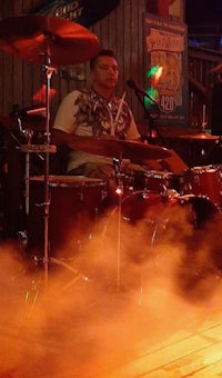 a man playing drums in front of smoke in a bar